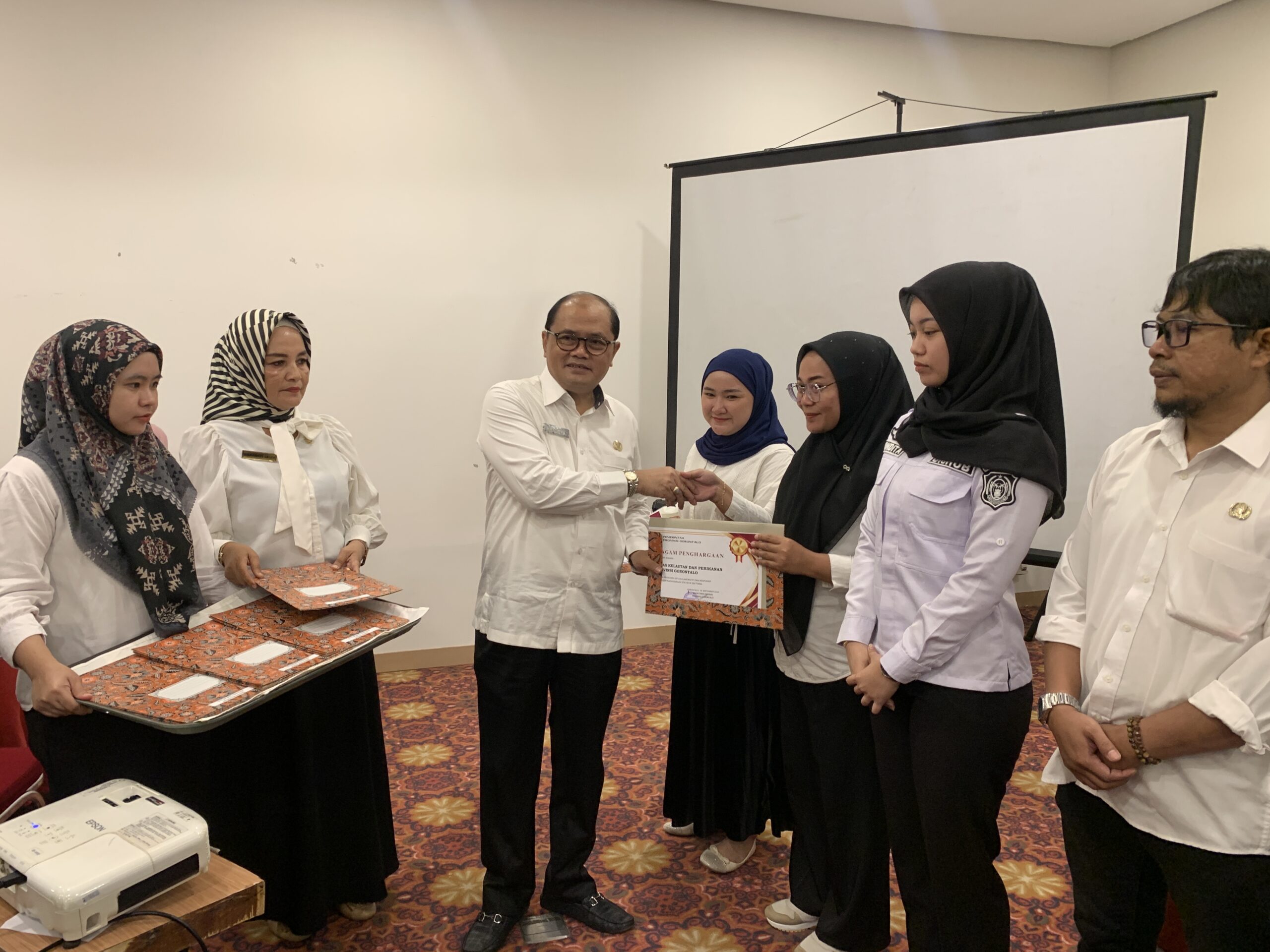 Plh. Sekdaprov Gorontalo Handoyo Sugiharto saat menyerahkan penghargaan sebagai produsen data kolaboratif dan responsif dalam penyelenggaraan statistik sektoral pada pelaksanaan Workshop Peningkatan Kapasitas ASN Pengelola Data di Hotel Fox, Kota Gorontalo, Rabu (18/9/2024